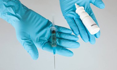 Hemşirenin elinde intranasal ve sıvı covid aşısı var.