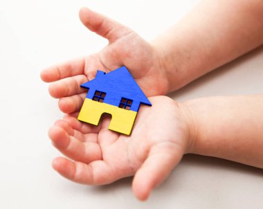 Ukrayna bayrağı renginde ahşap oyuncak evi tutan çocuk.