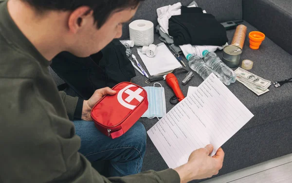 Young Man Packing Bag Documents Water Food First Aid Kit — Stock Photo, Image