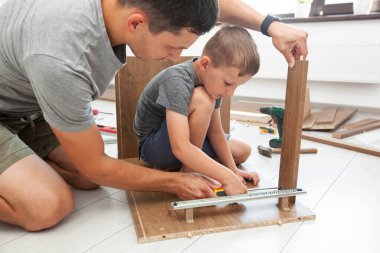 Baba ve oğul masayı birleştiriyor ve baba oğluna aletleri nasıl kullanacağını öğretiyor.
