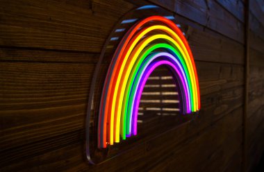 led neon rainbow hanging on the wooden wall