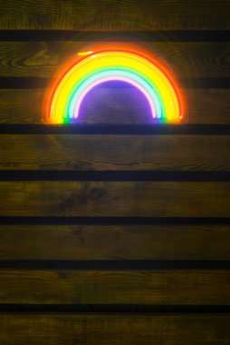 led neon rainbow hanging on the wooden wall