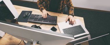 The guy in office working with the laptop and pc in the same time