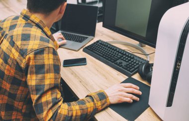 The guy in office working with the laptop and pc in the same time