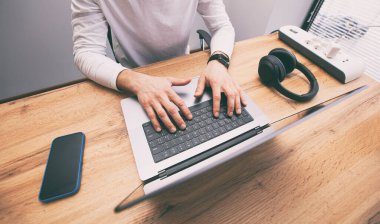 Young man working on laptop computer while sitting in coworking space. Freelance concept.