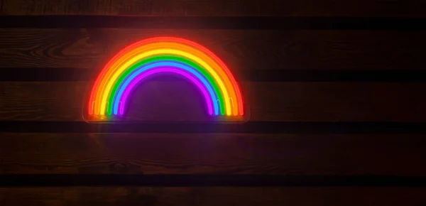 led neon rainbow hanging on the wooden wall