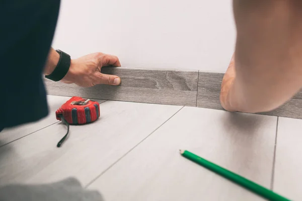 Worker is finishing floor installation and installing skirting board