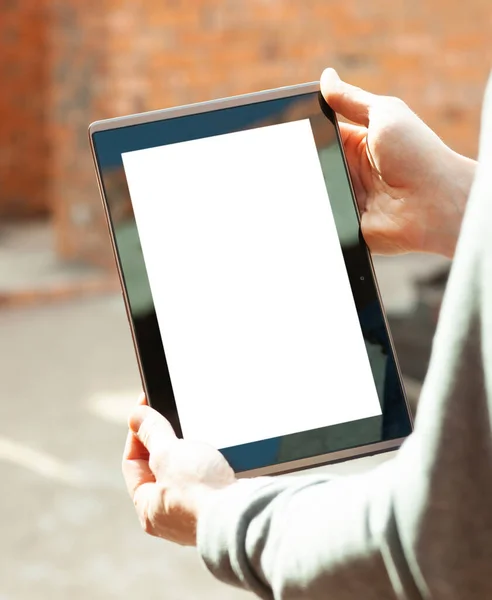 Construction worker holding digital tablet with blank screen in front of an unfinished house, repair, construction concept. Mockup