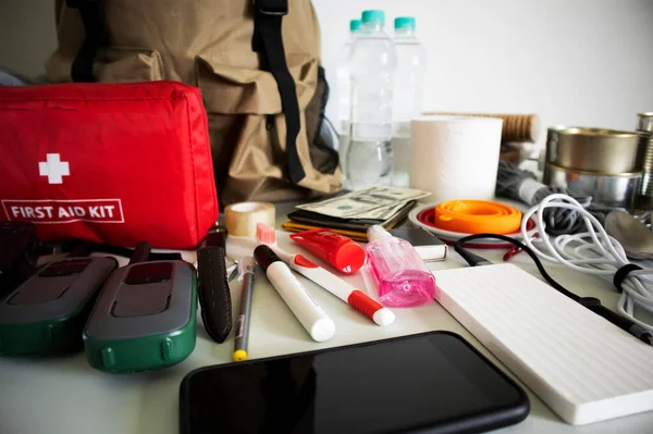 Rucksack Notfallausrüstung Auf Dem Tisch Dokumente Wasser Lebensmittel Verbandskasten Und — Stockfoto