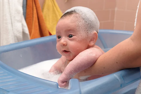 Cute baby in a bathtub with foam cap on his head — Stock Photo, Image