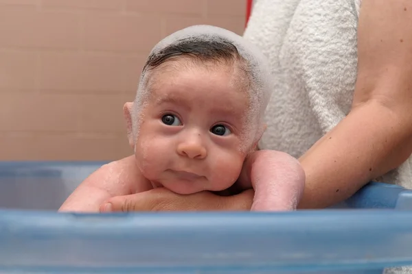 Cute baby in a bathtub with foam cap on his head — Stock Photo, Image