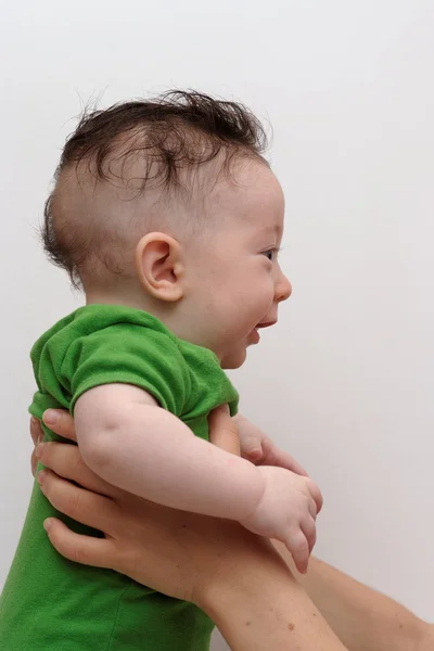 Lindo bebé sonriente sostenido por su madre vista de perfil — Foto de Stock