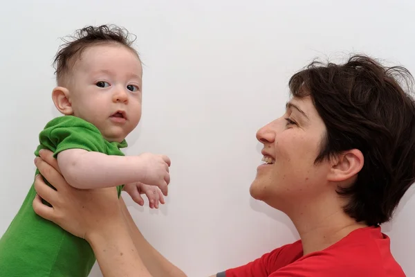 Lindo bebé sostenido por su madre sonriente mira hacia la cámara — Foto de Stock