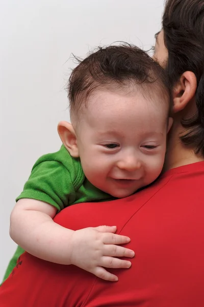 Rear view of cute smiling baby boy looking over mother shoulder — Stock Photo, Image