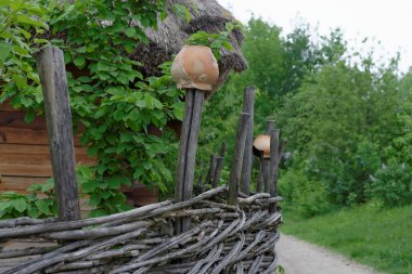Traditional lath fence around a farmer's house with clay pots on top of stakes in open air museum, Kiev, Ukraine clipart