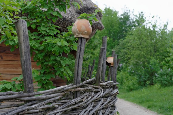 Traditional lath fence around a farmer's house with clay pots on top of stakes in open air museum, Kiev, Ukraine