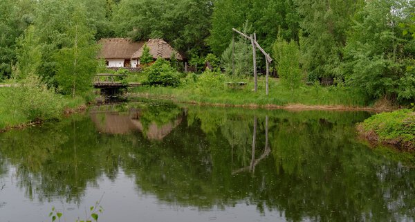 Traditional farmer's house reflecting in a pond in open air museum, Kiev, Ukraine