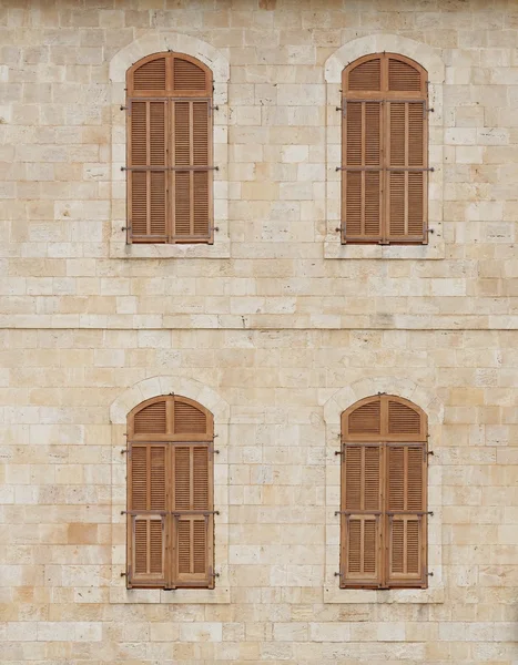 Muur van het oude gebouw met gesloten vensters Houten Jaloezieen vallende — Stockfoto