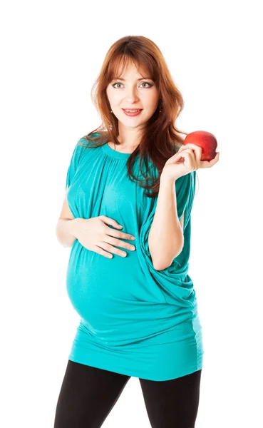 Беременная улыбающаяся женщина держит яблоко в руке — стоковое фото