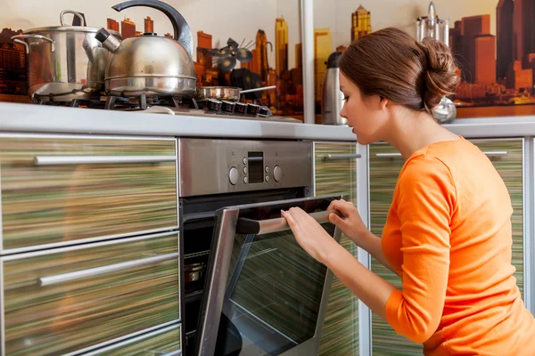 Een jonge vrouw is koken in de kachel — Stockfoto