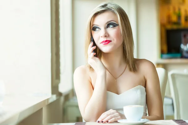 Eine Frau im Restaurant telefoniert mit einem Handy Stockbild