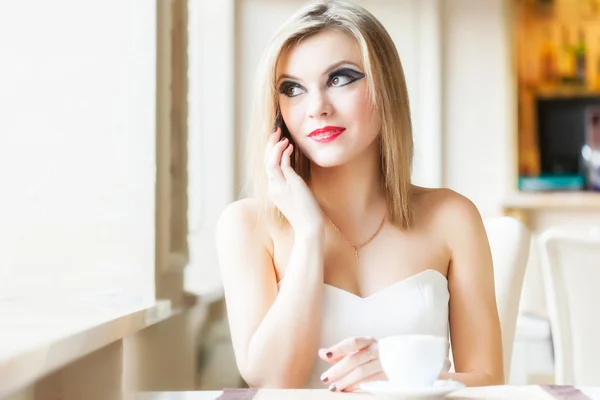 Een vrouw in het restaurant spreekt op een mobiele telefoon — Stockfoto