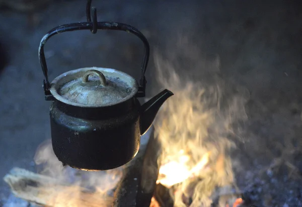 Wasserkocher aus Gusseisen hängt über dem Feuer lizenzfreie Stockfotos