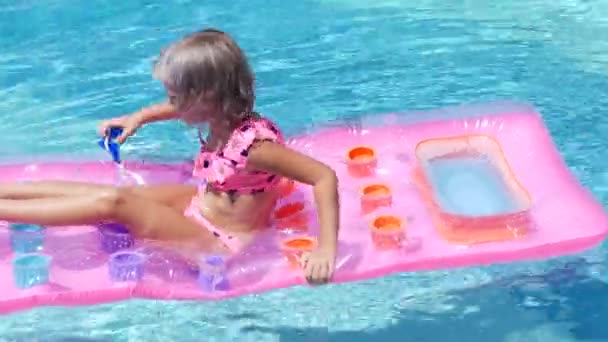 Blonde fille nage dans la piscine sur un matelas gonflable — Video