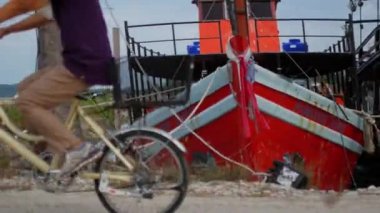 Teknelerle rıhtımdan geçen bisikletli bir adam.