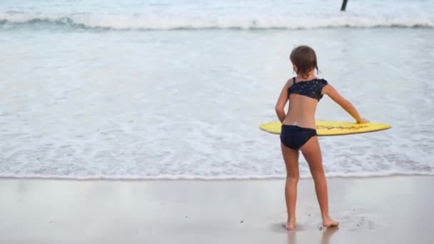 Ένα παιδί καβαλάει μια σανίδα στις ακτές ενός νησιού στις τροπικές περιοχές. — Αρχείο Βίντεο