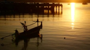 Deniz koyunda huzurlu, renkli bir gün batımı.
