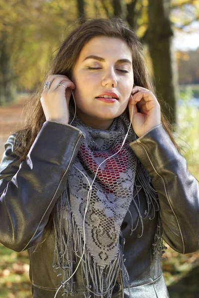 Kvinna lyssnar musik i parken — Stockfoto