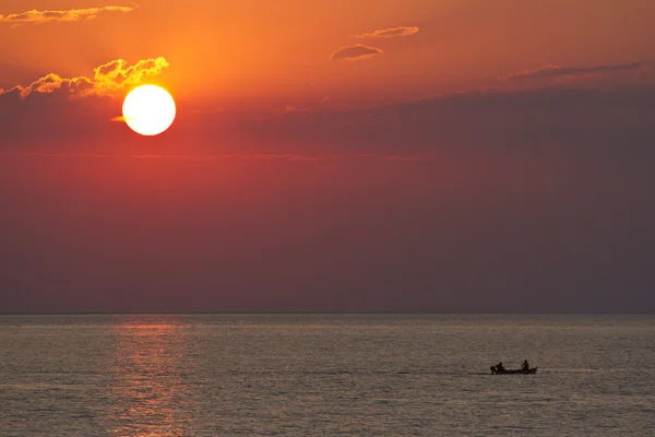 Sunset with silhouettes of paddling boat — Stock Photo, Image