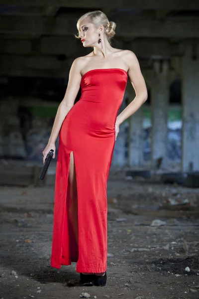 Žena s pistolí v červených šatech — Stock fotografie