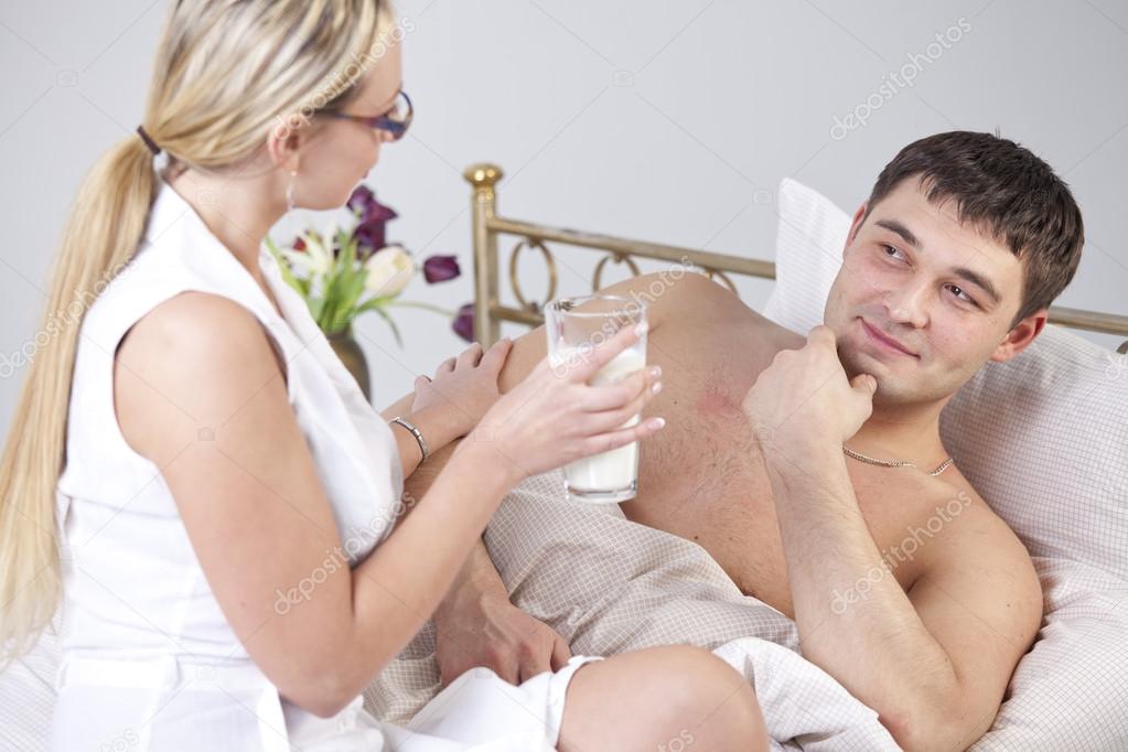 Woman with glass milk and sick man