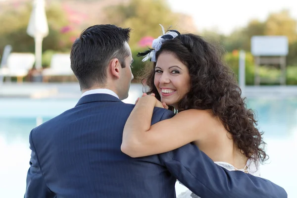 Jonge vrouw en man zitten bij het zwembad — Stockfoto