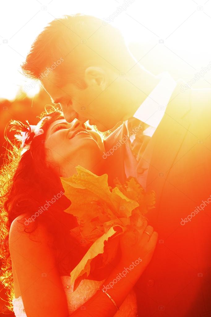 Young couple kissing at bright sunset