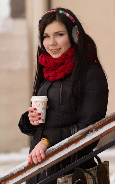 Söt tjej i öronproppar med kaffekopp — Stockfoto