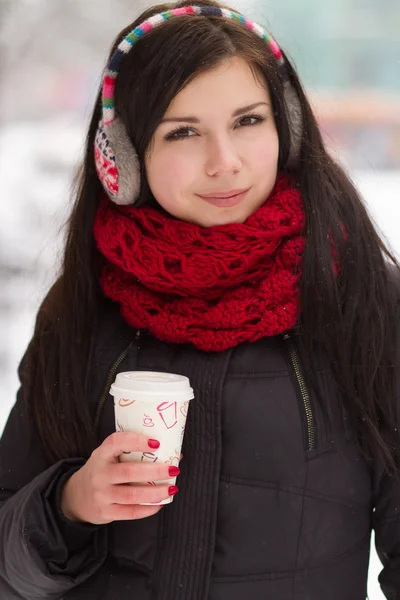 Leuk meisje in oordoppen met koffiekopje — Stockfoto