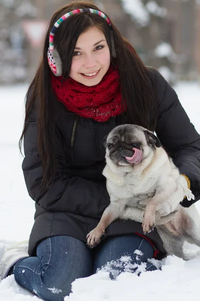 Teen girl with pug puppy in snow — Stock Photo, Image