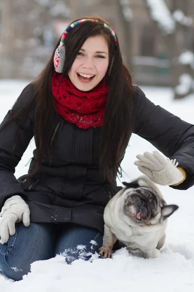 Teen flicka med mops valp i snö — Stockfoto