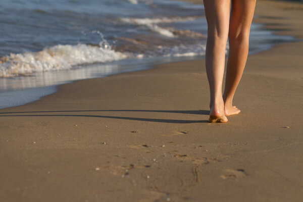 Feet of girl waking on sand