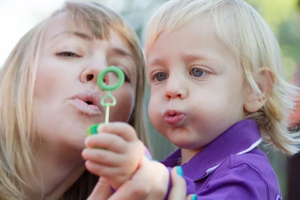 Мама і її дитина хлопчик дме бульбашки — стокове фото