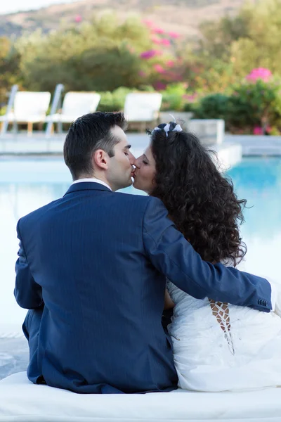 Jovem esposa e marido beijando na piscina — Fotografia de Stock