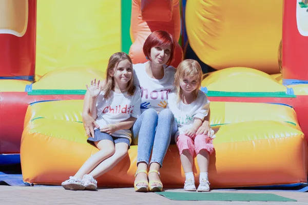 Mother and her daughters sitting on jumping castle — Stock Photo, Image