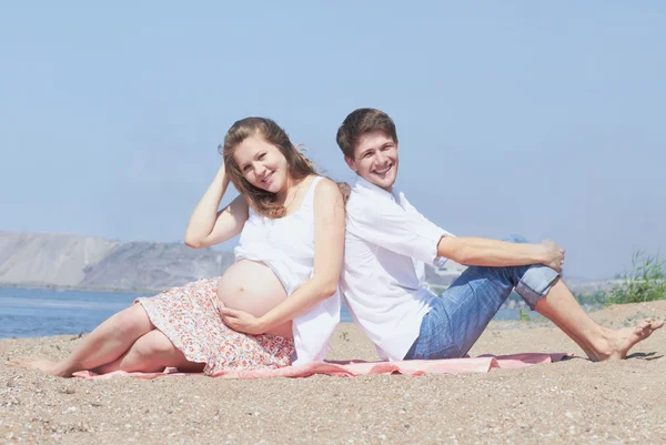 Gelukkige jonge zwangere familie op zee — Stockfoto