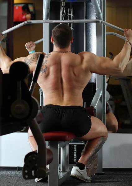 Hombre bombeado tirando de peso en el gimnasio — Foto de Stock