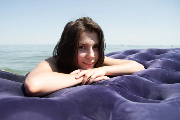 Menina tomando banho de sol no colchão de ar no mar — Fotografia de Stock