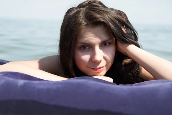 在海中的空气床垫上晒日光浴的女孩 — 图库照片
