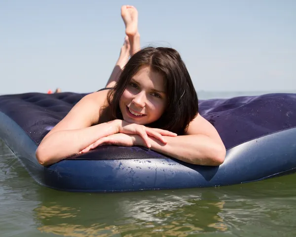 Chica tomando el sol en el colchón de aire en el mar — Foto de Stock